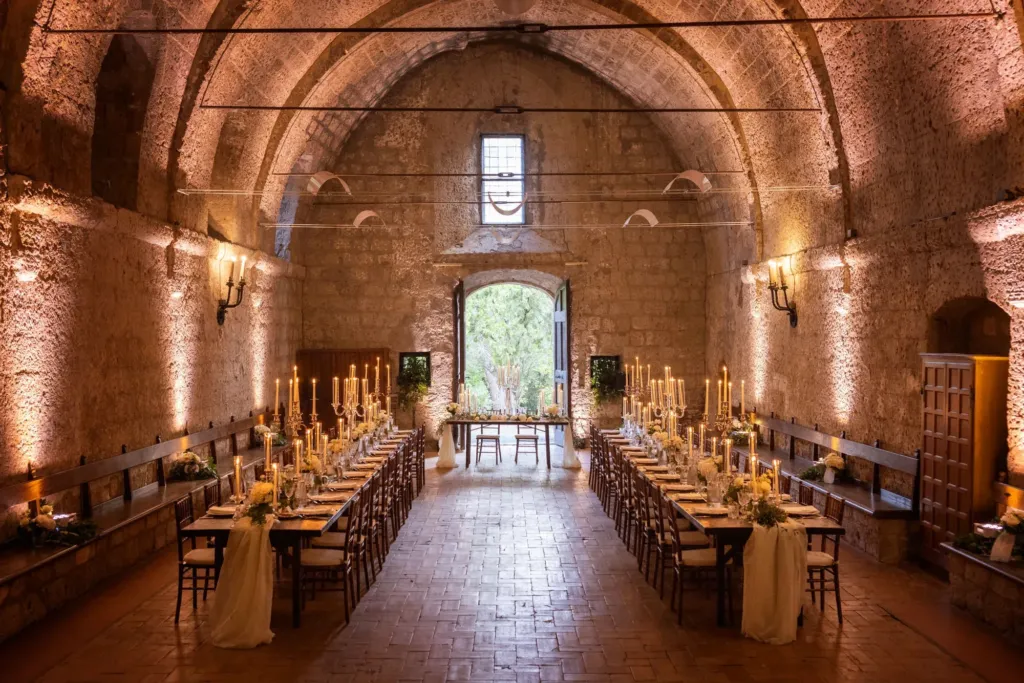 Long candlelit wedding tables in a vaulted stone hall, Italy