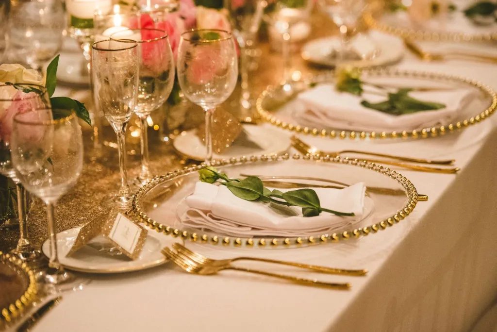 Wedding table with gold rimmed plates, glasses and pink roses