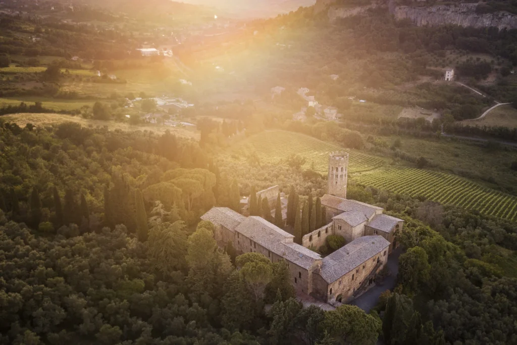 Aerial view of the Italian countryside with a historic abbey among vineyards and olive groves