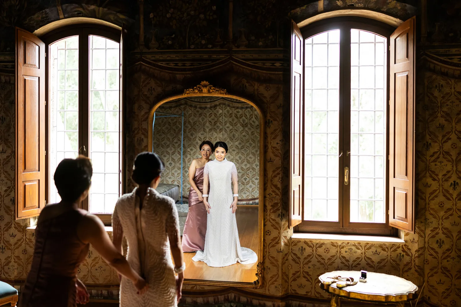 Bride getting ready in front of a gilded mirror in a castle, Italy