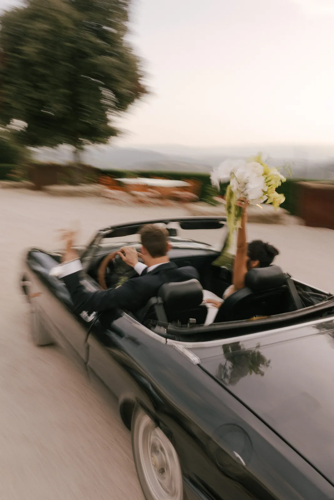 Bride and groom leaving in a vintage convertible, Italy