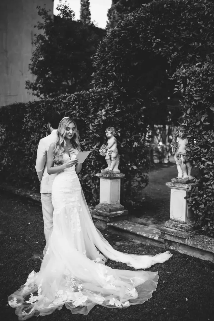 Bride reading a letter in the garden, black and white, Italy